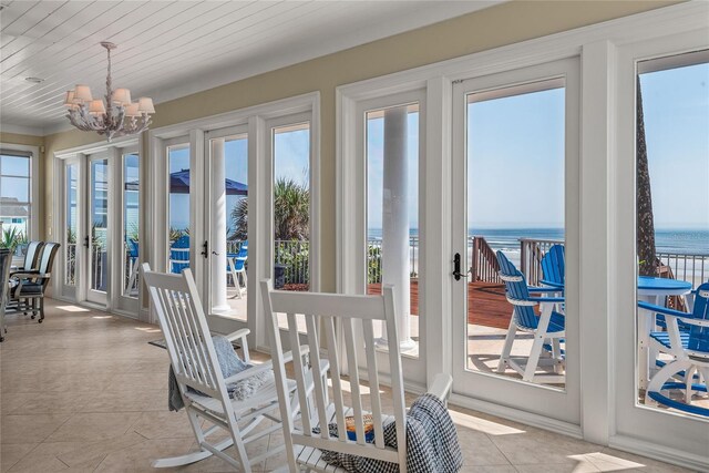 sunroom with a wealth of natural light, french doors, a chandelier, and a water view