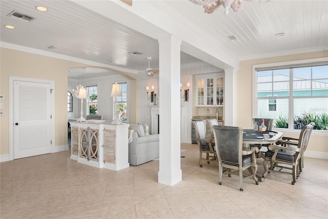 tiled dining space with ceiling fan with notable chandelier, wood ceiling, ornamental molding, and a healthy amount of sunlight