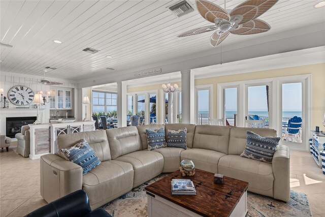 tiled living room with a water view, ceiling fan with notable chandelier, wood ceiling, and a healthy amount of sunlight