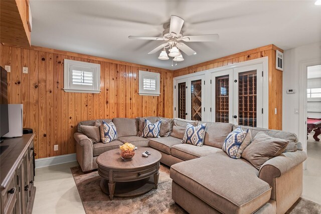 living room featuring a healthy amount of sunlight, ceiling fan, and wooden walls