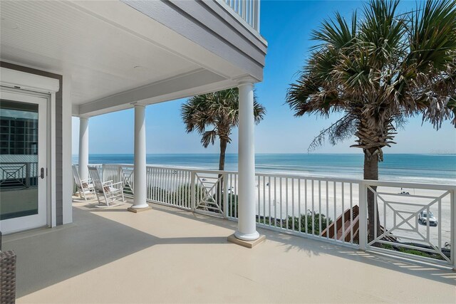 view of patio / terrace with a water view, a view of the beach, and a balcony