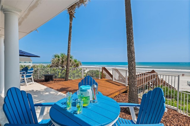 view of patio featuring a deck with water view and a beach view