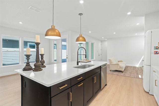 kitchen with a center island with sink, light wood-type flooring, sink, and white fridge