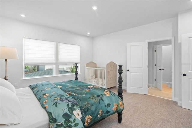 bedroom featuring ensuite bath and light colored carpet