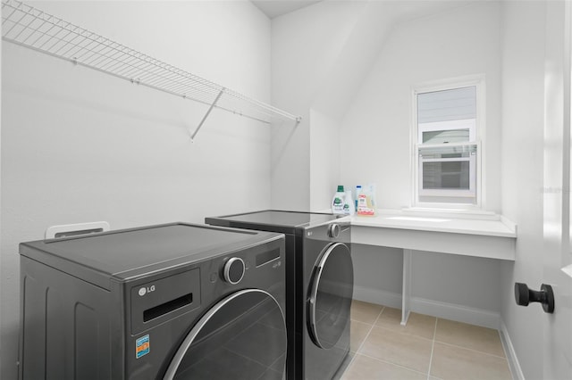 clothes washing area with light tile patterned floors and washer and clothes dryer