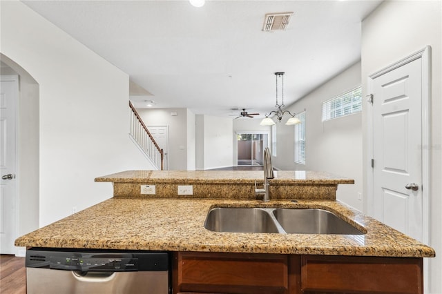 kitchen with light stone counters, hanging light fixtures, hardwood / wood-style flooring, dishwasher, and sink