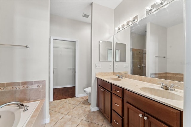 bathroom with dual bowl vanity, wood-type flooring, tiled bath, and toilet