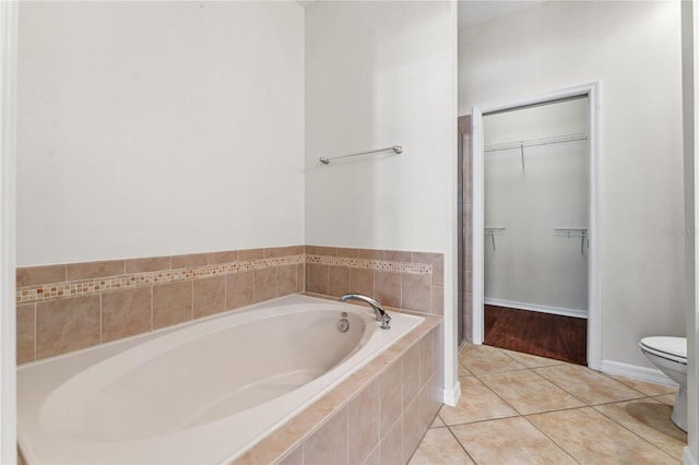 bathroom featuring wood-type flooring, tiled tub, and toilet