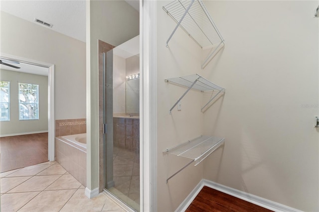 walk in closet featuring light wood-type flooring and ceiling fan