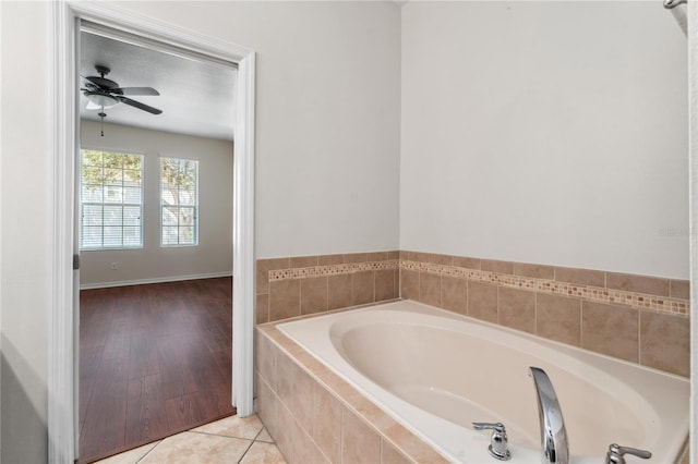 bathroom with ceiling fan, wood-type flooring, and tiled bath