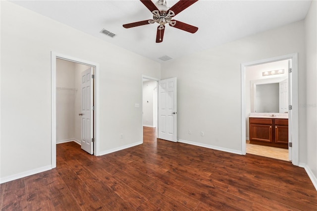 unfurnished bedroom featuring hardwood / wood-style floors, a spacious closet, ensuite bathroom, and ceiling fan