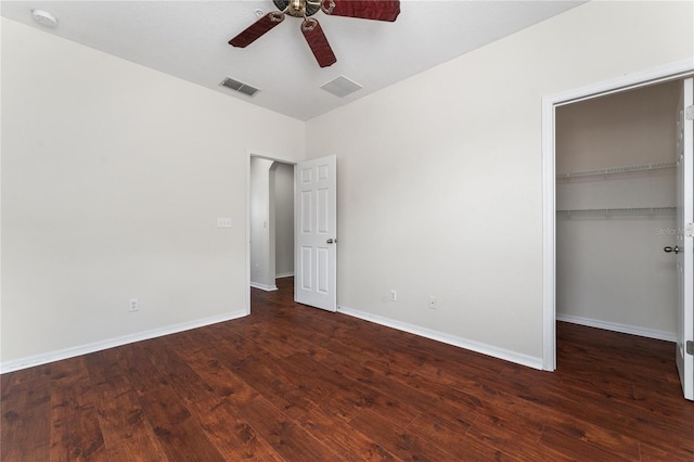 unfurnished bedroom with ceiling fan, a spacious closet, wood-type flooring, and a closet