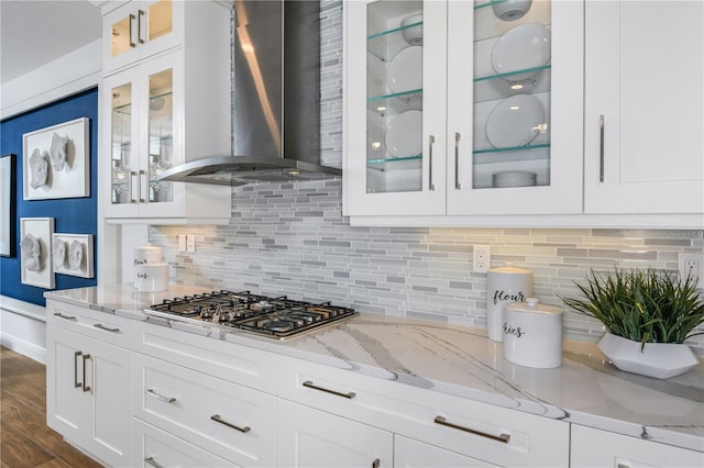 kitchen with stainless steel gas cooktop, decorative backsplash, wall chimney exhaust hood, and hardwood / wood-style flooring