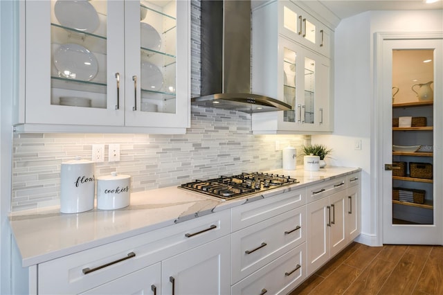 kitchen with backsplash, dark hardwood / wood-style flooring, wall chimney exhaust hood, and white cabinetry