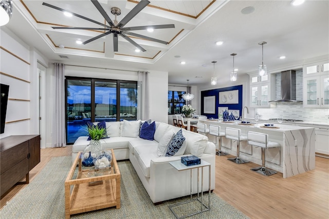 living room featuring ceiling fan, sink, coffered ceiling, and light hardwood / wood-style floors