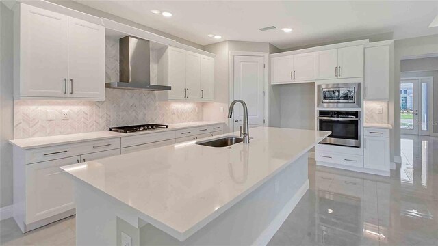 4990 Fairhope Cir, Lakewood Ranch, FL 34211 - kitchen featuring stainless steel appliances, a sink, wall chimney range hood, white cabinetry, and decorative backsplash