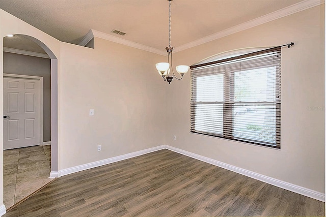 empty room featuring dark hardwood / wood-style flooring, ornamental molding, and an inviting chandelier