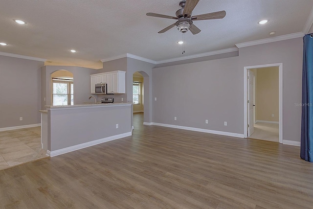 unfurnished living room with ceiling fan, crown molding, light hardwood / wood-style floors, and a textured ceiling