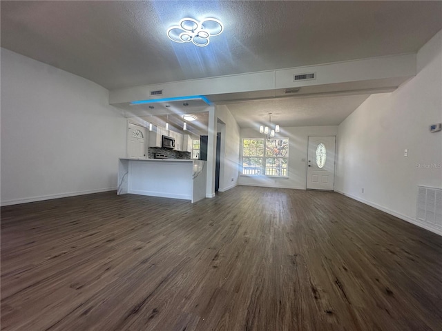 unfurnished living room featuring a notable chandelier, dark hardwood / wood-style floors, and a textured ceiling