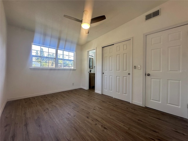 unfurnished bedroom featuring multiple closets, ceiling fan, dark hardwood / wood-style flooring, and vaulted ceiling