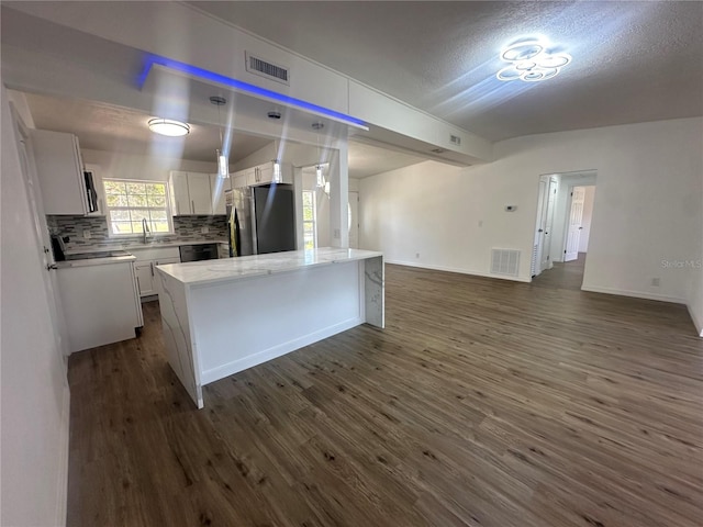 kitchen with stainless steel fridge, dark hardwood / wood-style flooring, backsplash, white cabinets, and a center island