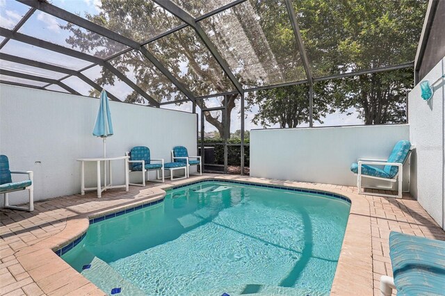 view of pool with glass enclosure and a patio