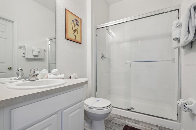 bathroom featuring a shower with door, toilet, vanity, and hardwood / wood-style floors