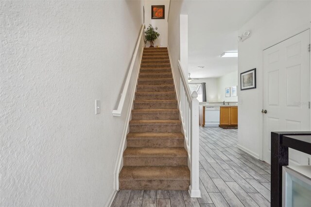 stairs featuring sink and hardwood / wood-style flooring