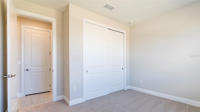 unfurnished bedroom with light carpet and a closet