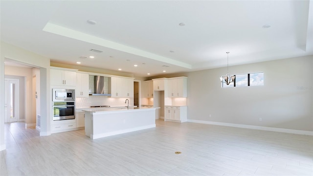 4845 Carova Way, Lakewood Ranch, FL 34211 - kitchen featuring wall chimney exhaust hood, stainless steel microwave, a sink, a chandelier, and decorative backsplash