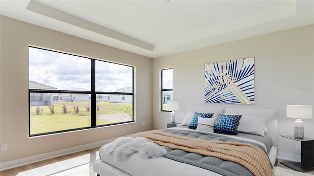 bedroom with a tray ceiling and light hardwood / wood-style flooring