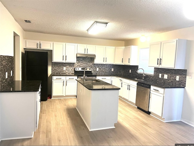 kitchen with under cabinet range hood, a center island with sink, a sink, visible vents, and appliances with stainless steel finishes