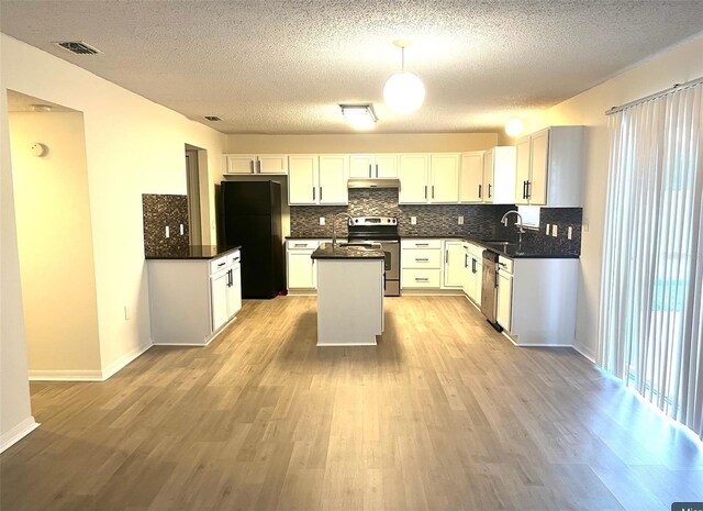 kitchen with light wood-type flooring, backsplash, appliances with stainless steel finishes, and a kitchen island