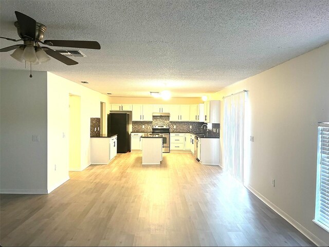 kitchen featuring light wood-type flooring, stainless steel electric range oven, black fridge, and white cabinets