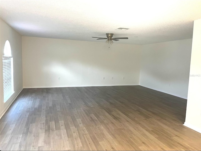 unfurnished room featuring a textured ceiling, visible vents, wood finished floors, and a ceiling fan