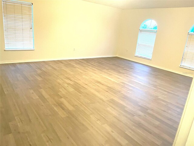 spare room featuring baseboards and wood finished floors