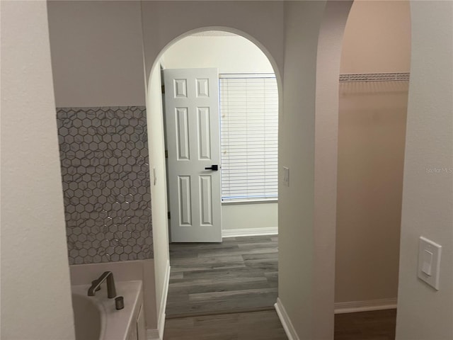 bathroom with a tub, baseboards, and wood finished floors