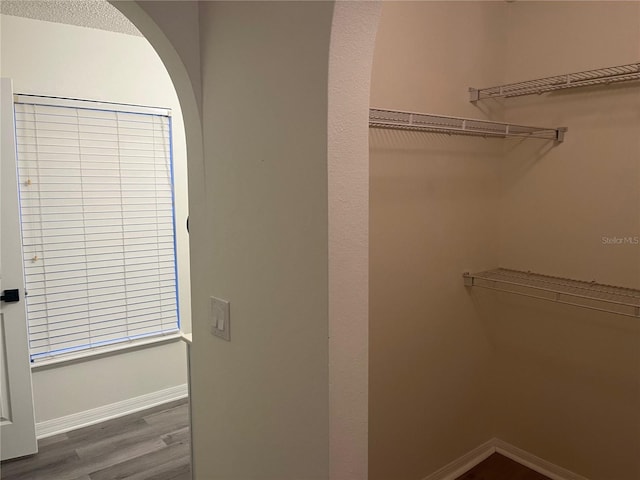 spacious closet featuring arched walkways and wood finished floors