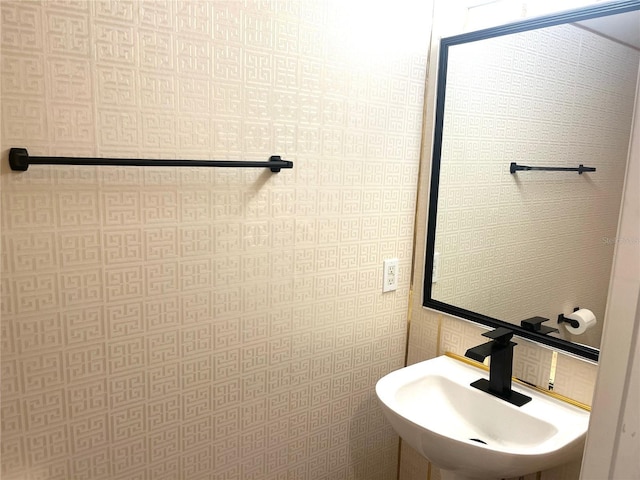 bathroom with wallpapered walls and a sink
