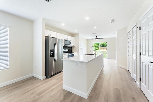 kitchen with stainless steel appliances, a kitchen island with sink, white cabinets, sink, and light hardwood / wood-style floors