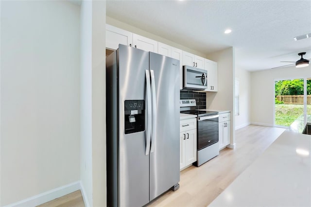 kitchen featuring white cabinets, appliances with stainless steel finishes, light hardwood / wood-style flooring, and decorative backsplash