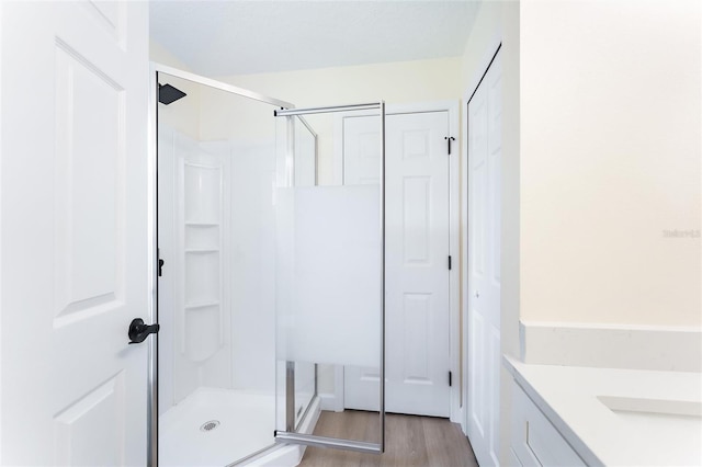 bathroom with hardwood / wood-style flooring, a shower with door, and vanity