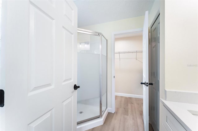 bathroom with a textured ceiling, vanity, hardwood / wood-style floors, and a shower with shower door