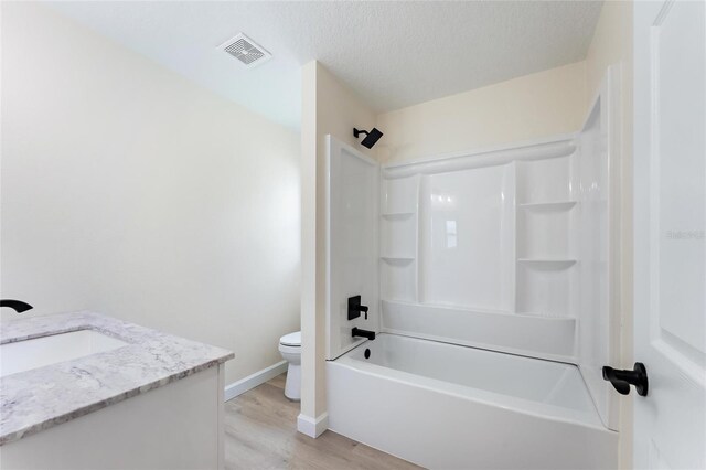 full bathroom featuring a textured ceiling, toilet, vanity, shower / bathing tub combination, and hardwood / wood-style floors