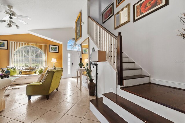 stairway featuring ceiling fan, lofted ceiling, and tile patterned floors