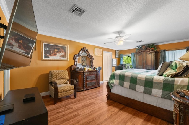 bedroom with a textured ceiling, ceiling fan, crown molding, and wood-type flooring