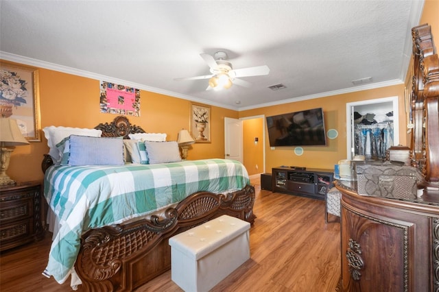 bedroom featuring a spacious closet, light wood-type flooring, a closet, and crown molding