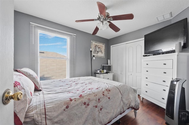 bedroom with ceiling fan, dark wood-type flooring, and a closet