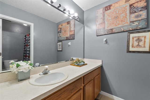 bathroom featuring toilet, a textured ceiling, and vanity