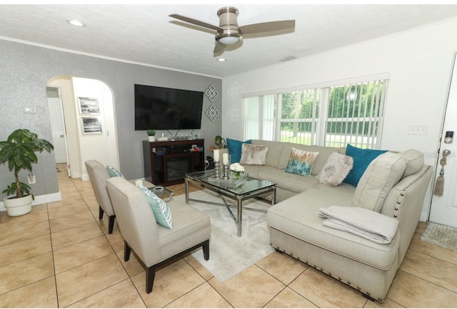 tiled living room with ceiling fan and ornamental molding